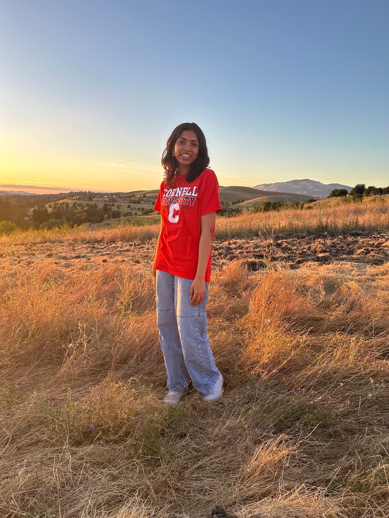 Oshin Rex outdoors at sunset, wearing a Cornell University shirt